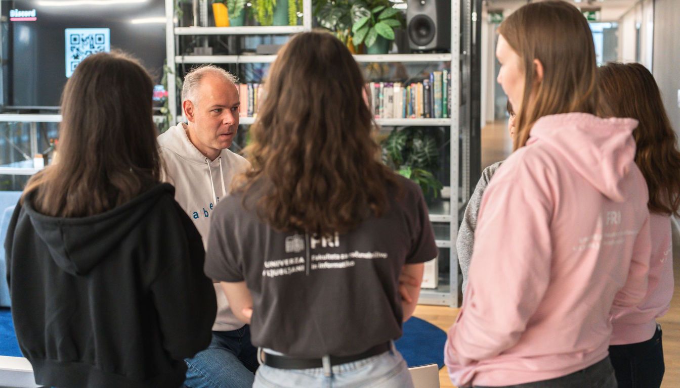 Mentor iz Abeliuma se pogovarja s skupino študentk in študentov na hekatonu AdaHack